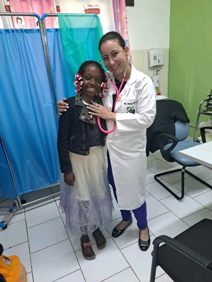 Médica da Clínica Medisaf com estetoscópio rosa junto de uma criança